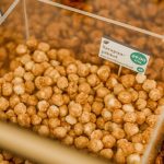 Close-up view of hazelnuts in a transparent container at a market stall.